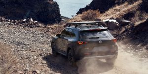2024 Mazda CX-50 driving on a dirt and rocky road headed toward the beach 