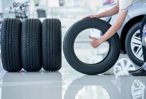 4 new tires that change tires in the auto repair service center, blurred background, the background is a new car in the stock blur for the industry, a four-wheeled tire set at a large warehouse | Vancouver, WA
